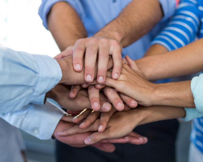 Multiple hands stacked together in a show of unity and teamwork.